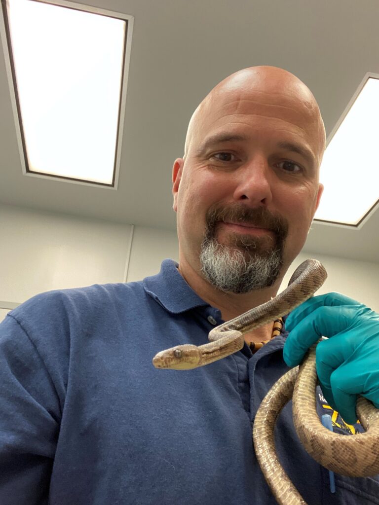 Dr. Minter smiles with the Virgin Island boa in his hand during the exam